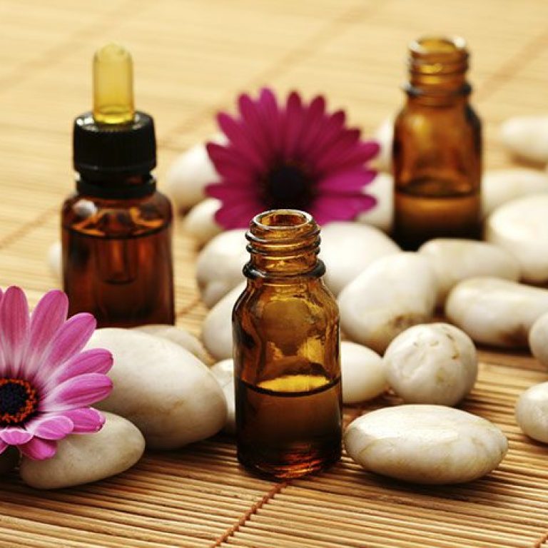 bottles of essence oil with pink flowers - beauty treatment